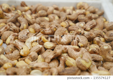 Cashew nuts in their shells spread across a market stall display Cashew nuts in their shells spread across a market stall display 135574127