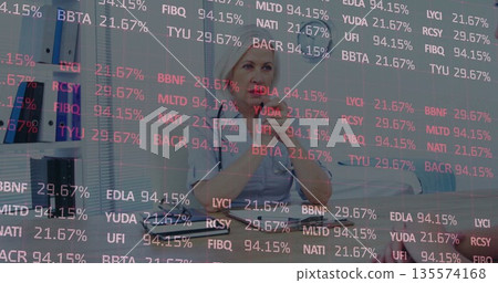 Doctor consulting patient in clinic in scrubs with stethoscope at desk, with clipboard and binders 135574168