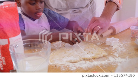 Pressing star-shaped cutter, father and son shaping dough on home kitchen countertop with sprinkles Pressing star-shaped cutter, father and son shaping dough on home kitchen countertop with sprinkles 135574190