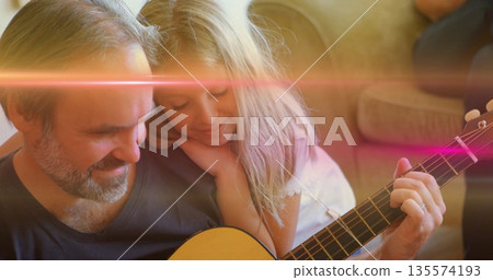 Playing acoustic guitar, bearded father guiding daughter on sofa in living room, warm sunlight glow Playing acoustic guitar, bearded father guiding daughter on sofa in living room, warm sunlight glow 135574193