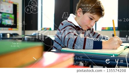 Focusing student in striped sweater writing in notebook at class desk, pencil books bulletin board 135574208