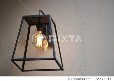Elegant hanging lantern with warm light on plain wall Elegant hanging lantern with warm light on plain wall 135574214