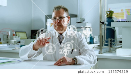 Reaching male scientist wearing lab coat tapping user-avatar icons at bench, periodic table poster Reaching male scientist wearing lab coat tapping user-avatar icons at bench, periodic table poster 135574219