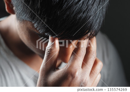 Young person showing deep contemplation or stress indoors 135574269