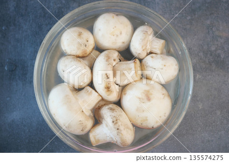 Fresh white mushrooms soaking in water for meal preparation Fresh white mushrooms soaking in water for meal preparation 135574275