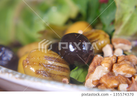 Grilled olives and walnuts on a fresh green salad plate Grilled olives and walnuts on a fresh green salad plate 135574370