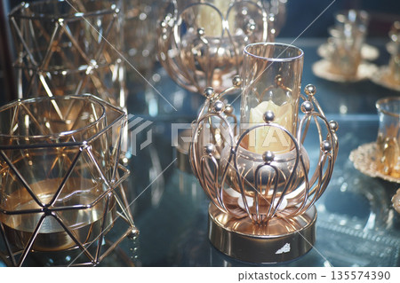 Elegant candle holders arranged on a glass display surface Elegant candle holders arranged on a glass display surface 135574390