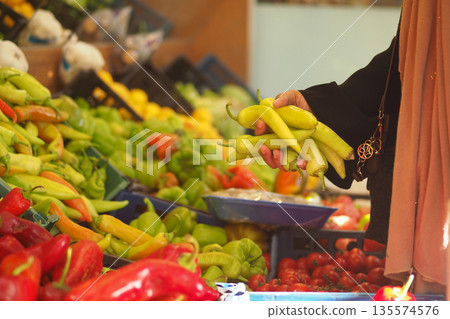 Person holding peppers at a market in the afternoon Person holding peppers at a market in the afternoon 135574576