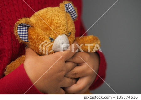 Child holds stuffed bear in hands indoors 135574610