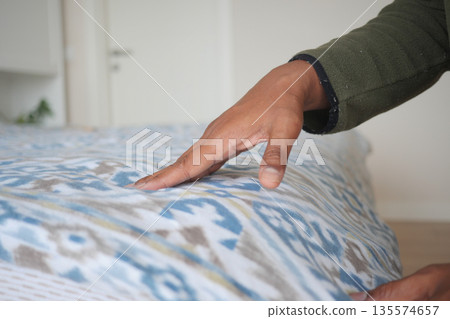 Hand touches fabric in home setting during daylight 135574657