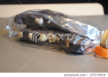 Chocolate bars with nuts in clear packaging on a table 135574658