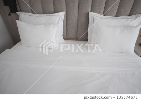 Bed with white sheets and pillows in a simple room Bed with white sheets and pillows in a simple room 135574673
