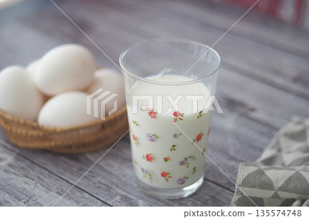 Fresh milk and eggs on a wooden table in a kitchen setting Fresh milk and eggs on a wooden table in a kitchen setting 135574748