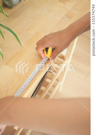 Measuring wood with tape on a wooden table Measuring wood with tape on a wooden table 135574749