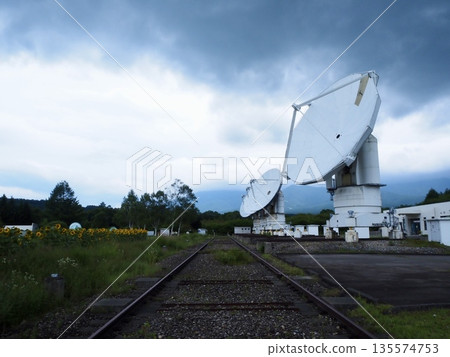 A large parabolic antenna installed next to the railroad tracks A large parabolic antenna installed next to the railroad tracks 135574753