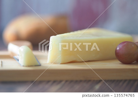 Cheese and grapes on a wooden board in a kitchen setting 135574765