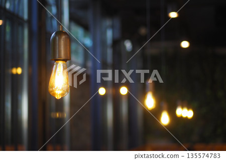 Hanging lights illuminate indoor space in evening setting Hanging lights illuminate indoor space in evening setting 135574783