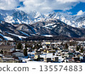 The majestic Hakuba Sanzan mountains and the townscape of Hakuba in winter, Hakuba Village, Nagano Prefecture (aerial shot by drone) 135574883