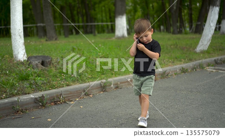 Three year old boy walking in park talking on phone 4k Three year old boy walking in park talking on phone 4k 135575079