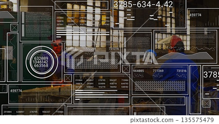 Two carpenters operating table saw and cutting wooden plank in workshop, with measuring tape 135575479