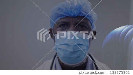 Posing senior male doctor wearing surgical cap and mask and lab coat in clinic, with stethoscope 135575501