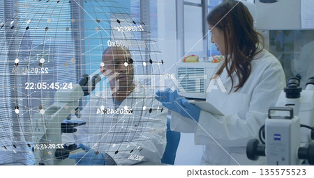 Discussing hologram data two scientists wearing white lab coats at lab bench, using tablet computer Discussing hologram data two scientists wearing white lab coats at lab bench, using tablet computer 135575523