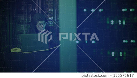 IT technician in hoodie configuring laptop at data center with racks and LED panel copy space IT technician in hoodie configuring laptop at data center with racks and LED panel copy space 135575617
