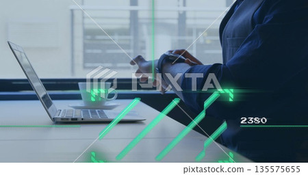 Middle Eastern professional checking smartwatch at office desk with laptop, mug and HUD, copy space Middle Eastern professional checking smartwatch at office desk with laptop, mug and HUD, copy space 135575655