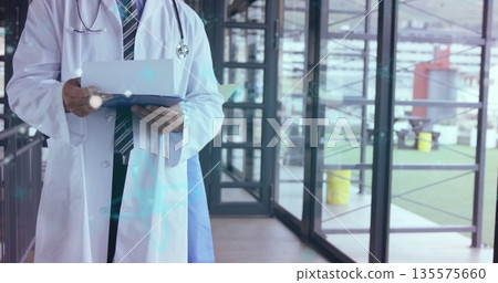 Doctor checking records and holding blue clipboard in clinic corridor, with stethoscope, copy space 135575660