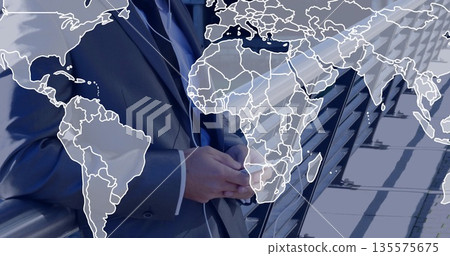 Standing man in dark suit clasping hands on rooftop terrace, with glass railing and map overlay 135575675