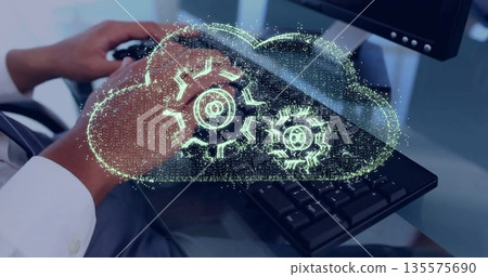 Showing worker wearing shirt typing on keyboard at office desk, with holographic cloud gear icon Showing worker wearing shirt typing on keyboard at office desk, with holographic cloud gear icon 135575690