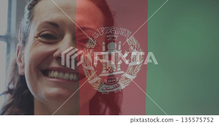Smiling mid adult woman showing teeth on digital Afghanistan flag overlay, with emblem, copy space Smiling mid adult woman showing teeth on digital Afghanistan flag overlay, with emblem, copy space 135575752