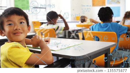 Boy in yellow Tshirt leaning on desk in classroom with translucent math overlay, copy space Boy in yellow Tshirt leaning on desk in classroom with translucent math overlay, copy space 135575877