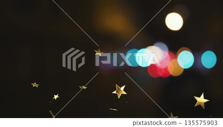 Floating gold star-shaped confetti pieces drifting through nighttime venue, with colorful bokeh Floating gold star-shaped confetti pieces drifting through nighttime venue, with colorful bokeh 135575903