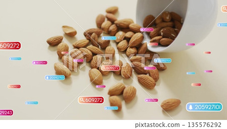 Showing raw almonds spilling from white ceramic cup on light surface, with digital metric overlays Showing raw almonds spilling from white ceramic cup on light surface, with digital metric overlays 135576292
