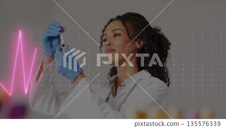 Pipetting scientist in lab coat transferring red liquid into test tube at bench, with ECG overlay 135576339