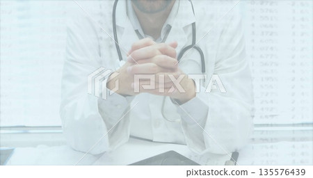 Sitting doctor wearing white coat reviewing digital tablet in consultation room, with stethoscope Sitting doctor wearing white coat reviewing digital tablet in consultation room, with stethoscope 135576439
