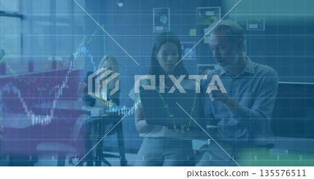 Collaborating coworkers wearing business attire pointing at laptop in meeting room, stock charts 135576511