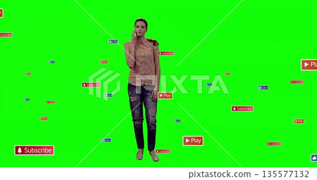 Presenter holding smartphone to ear in green screen, with floating subscribe, play and like icons 135577132