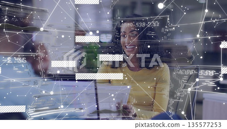 Smiling mid adult female holding documents at open plan office, displaying data overlays 135577253
