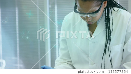 Leaning technician concentrating on task at lab bench, with goggles, lab coat and glove, copy space Leaning technician concentrating on task at lab bench, with goggles, lab coat and glove, copy space 135577264