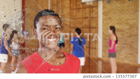Standing boy in red shirt smiling in school gymnasium, with globe overlay, volleyball net and hoop 135577307