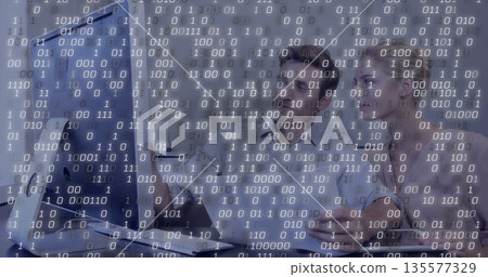 Collaborating two professionals in business attire examining code in office with monitor mouse Collaborating two professionals in business attire examining code in office with monitor mouse 135577329