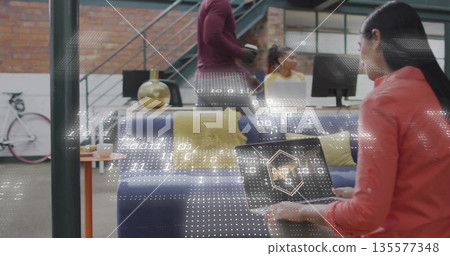 Working Asian woman using laptop on navy-blue couch by gold lamp at office lounge, copy space 135577348