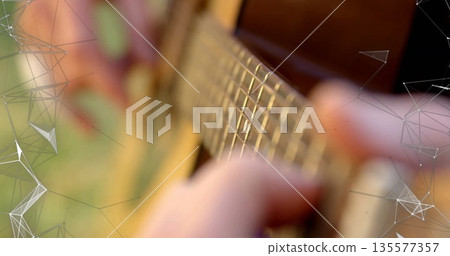 Pressing musician's fingers playing chords on acoustic guitar fretboard in yard, with overlay Pressing musician's fingers playing chords on acoustic guitar fretboard in yard, with overlay 135577357
