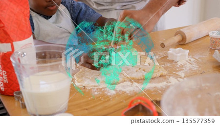 Kneading parent and child shaping dough in home kitchen, with rolling pin and cookie cutters 135577359
