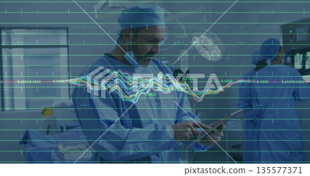 Reviewing patient data, lead surgeon using tablet in operating room, with lights and monitors Reviewing patient data, lead surgeon using tablet in operating room, with lights and monitors 135577371