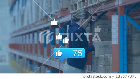 Leaning woman in navy blazer inspecting box in warehouse aisle, with floating thumbs-up, copy space Leaning woman in navy blazer inspecting box in warehouse aisle, with floating thumbs-up, copy space 135577373