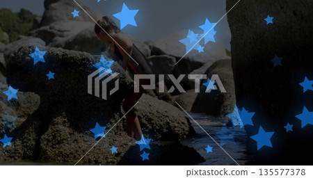 Climbing child wearing black red striped swimsuit traversing granite boulders at clear tidal pool Climbing child wearing black red striped swimsuit traversing granite boulders at clear tidal pool 135577378