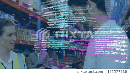 Warehouse team in vests reviewing process on warehouse floor, with tablet and digital code overlay 135577386